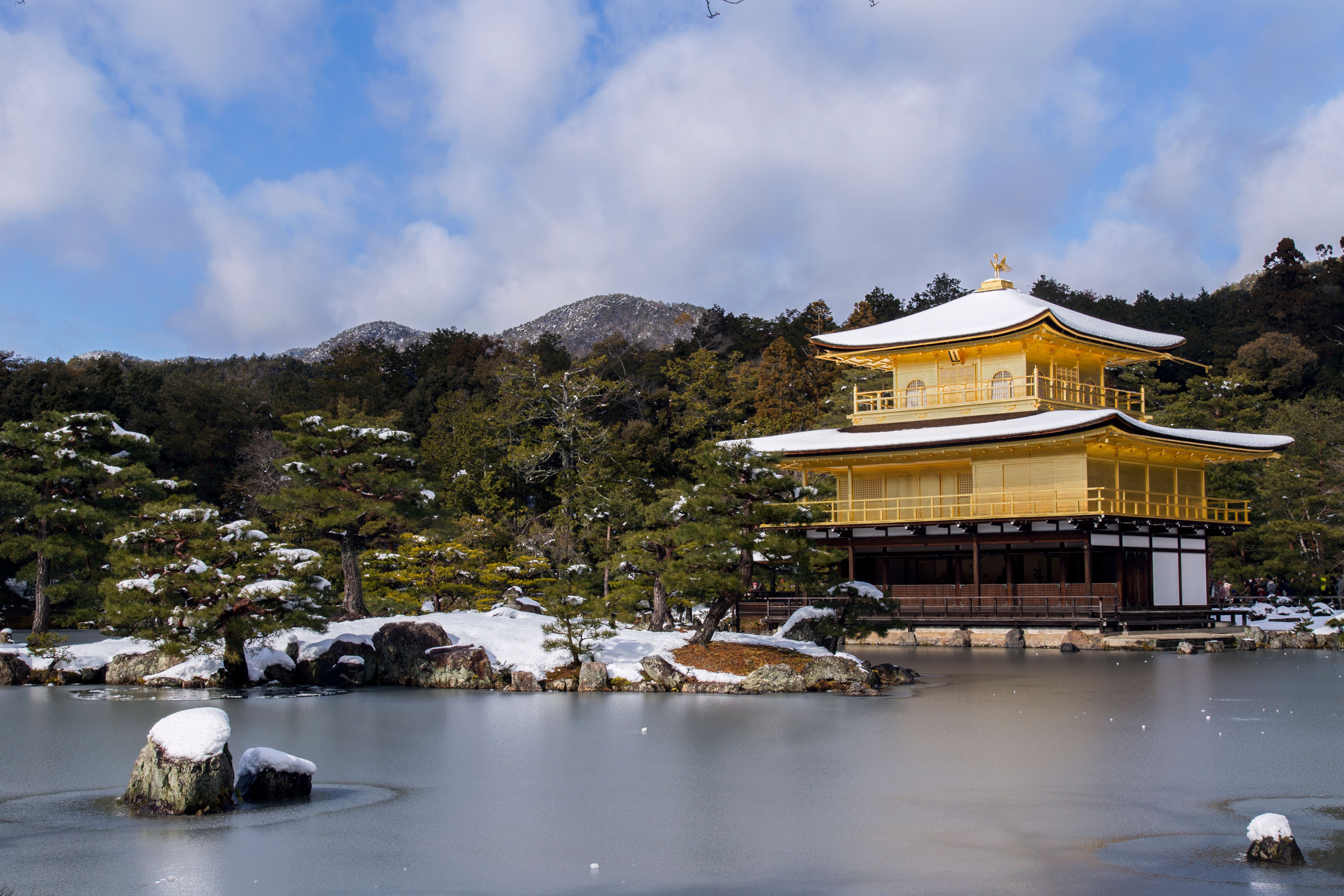 Kyoto's Golden Pavilion reflected in a serene snow-covered landscape during winter.