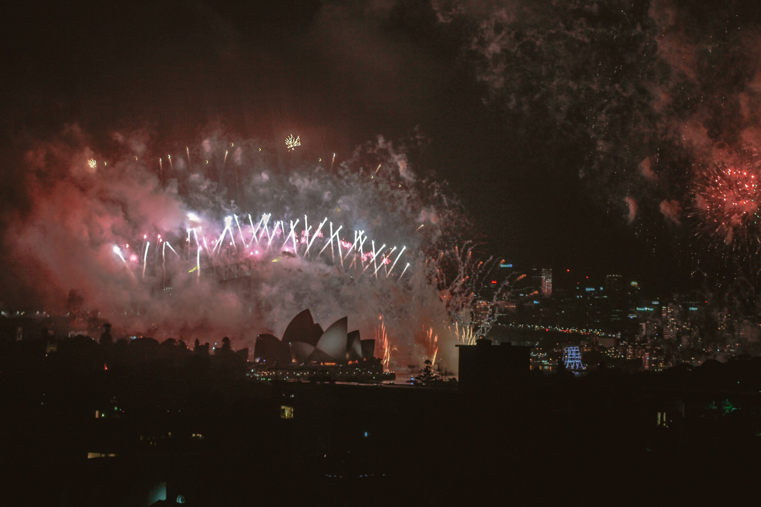 Fireworks light up the night sky above Sydney Harbour, with the Opera House in view.